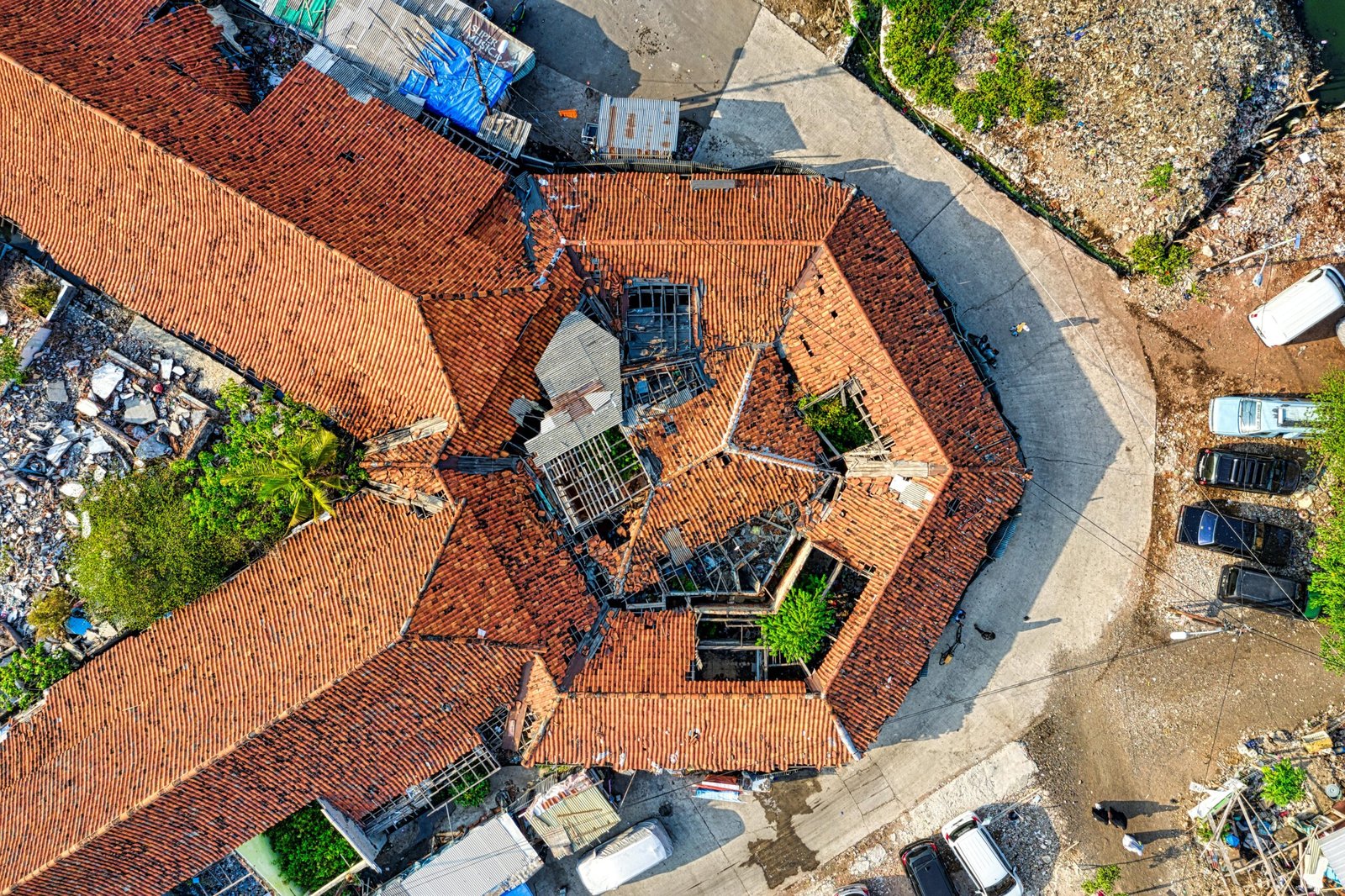 Aerial drone shot capturing a rooftop in Jakarta, showcasing unique architectural design with fallen debris around.